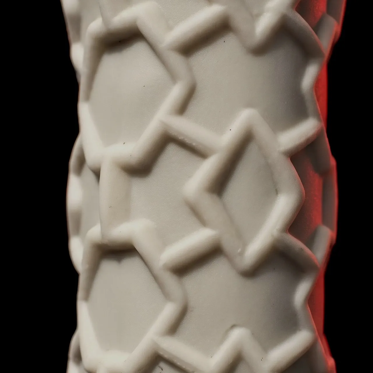 Macro du manche en silicone alvéolé d'une raquette SCUD, avant la pose du grip : un relief d'étoiles et de losanges imbriqués